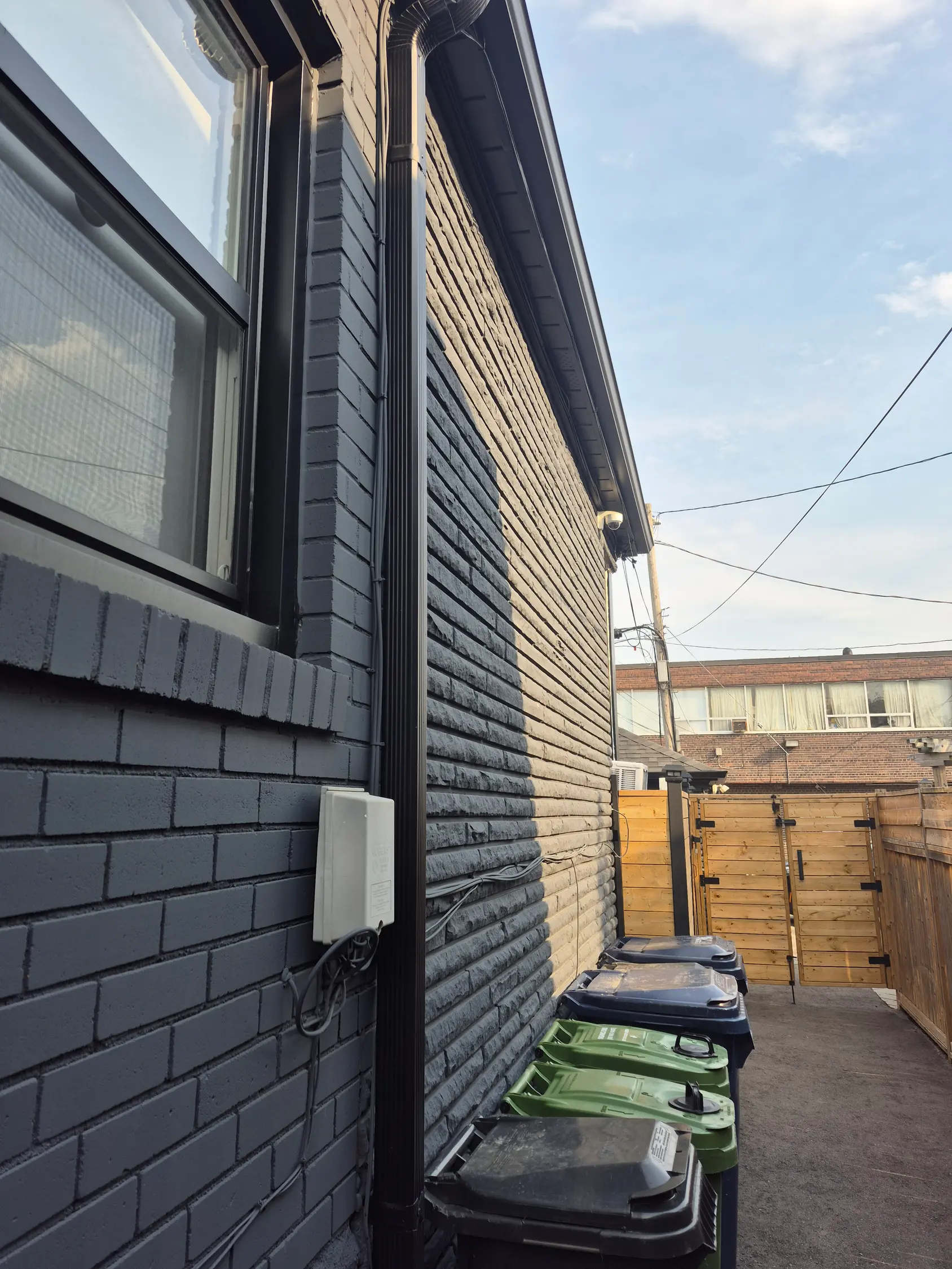 A Toronto exterior repaint: the coating choice matters less than whether the overnight temperature holds for the 48 hours after it goes on Exterior of a Toronto home with freshly painted dark brickwork, soffit, and eaves
