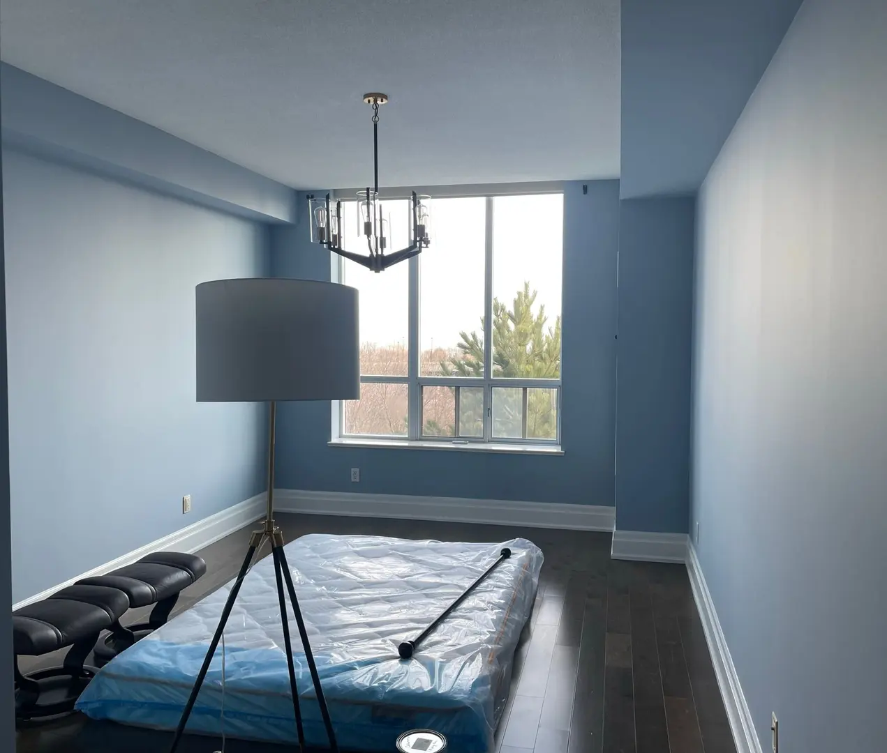 Toronto bedroom painted in a soft blue with dark hardwood floors and a pendant light