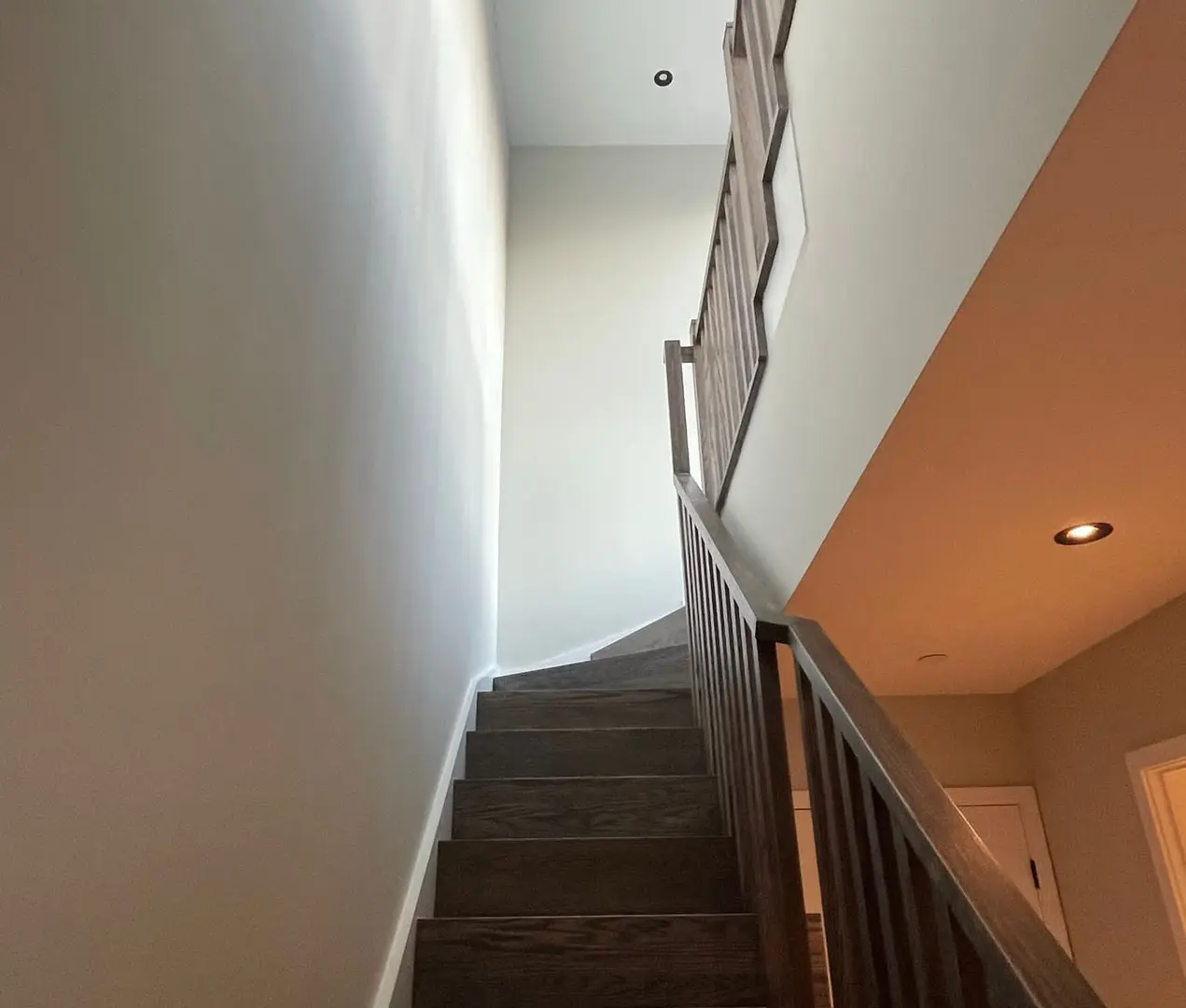 Interior staircase with white walls, a warm terracotta accent wall, dark-stained treads and pot lights in a Toronto home